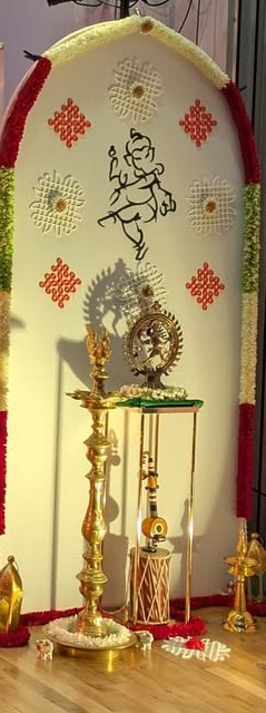 Floral arch backdrop with Ganesh rangoli design and diya lamp