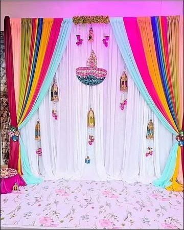 Rainbow silk drape ceremony backdrop with hanging diya ornaments
