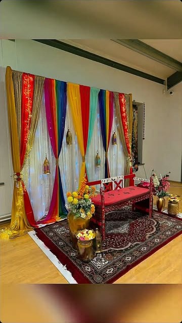 Rainbow silk drape backdrop with red ceremonial bench and rug